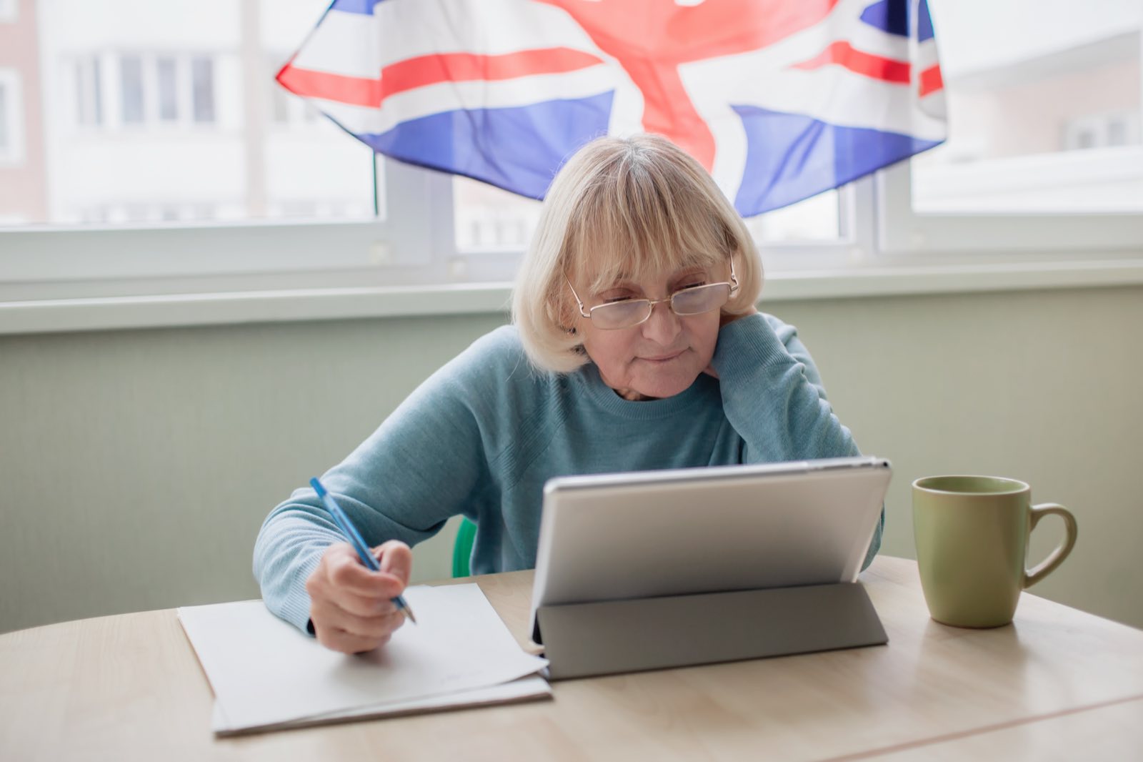 A retired woman filling in forms with a tablet at her table