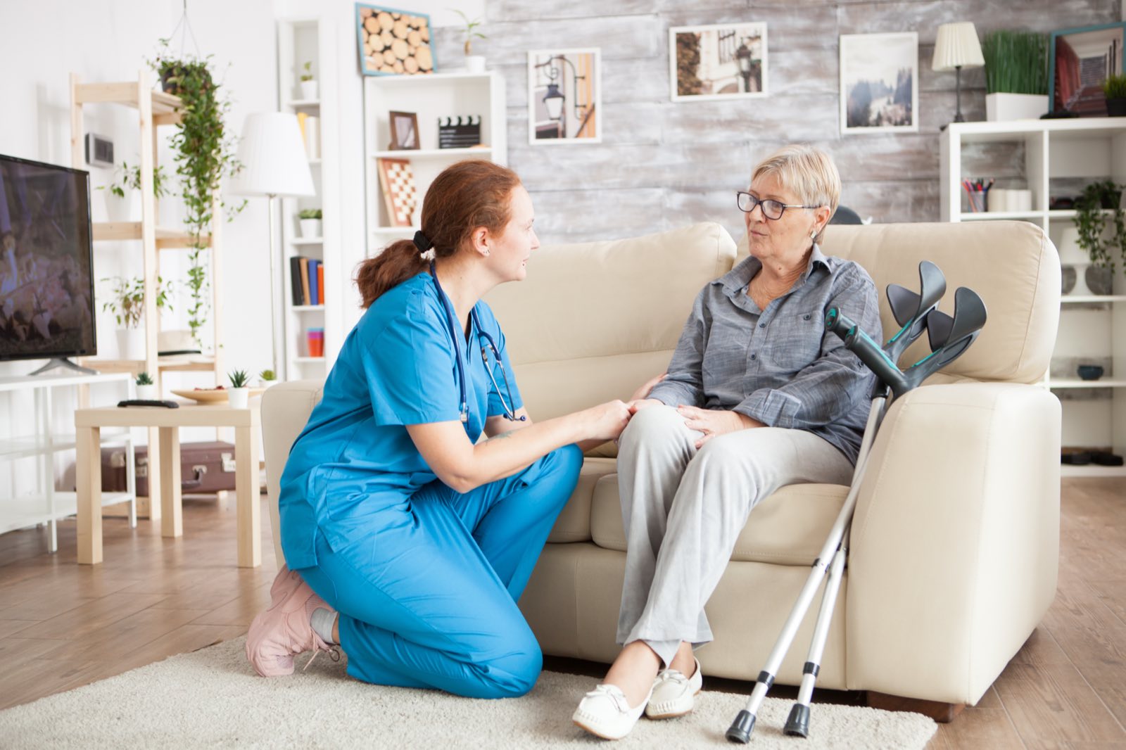 A nurse talking with an older woman sitting on a sofa at home
