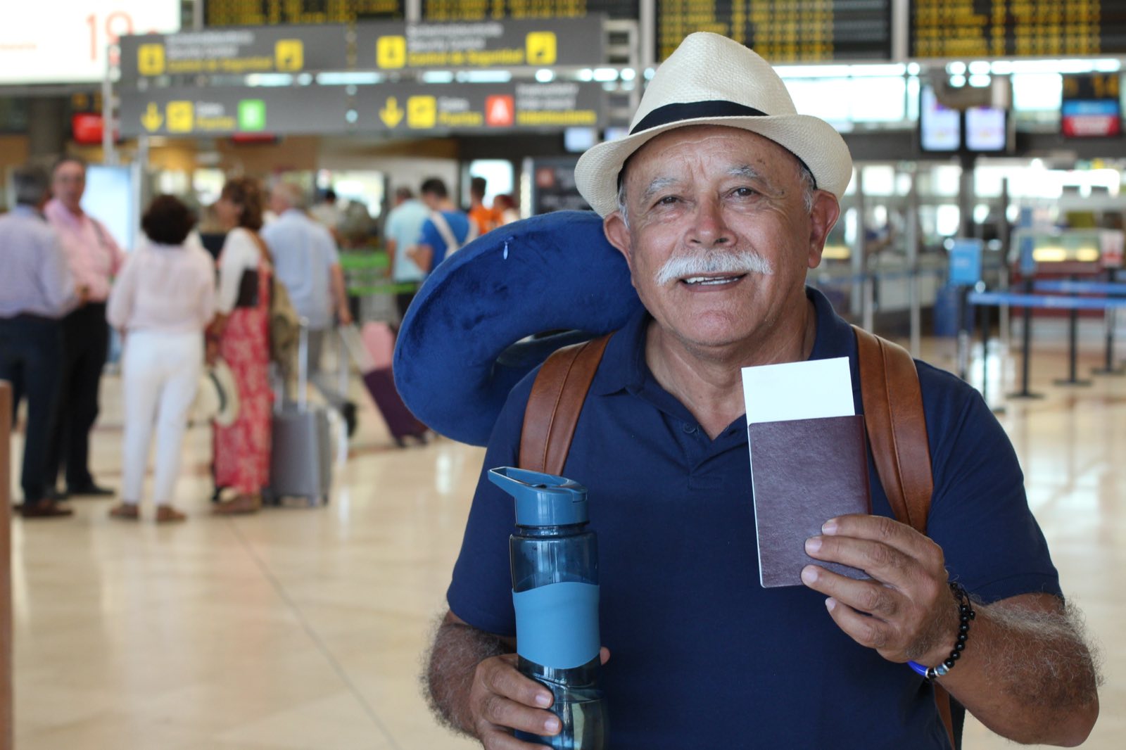 A smiling retired traveller holding his passport in an airport
