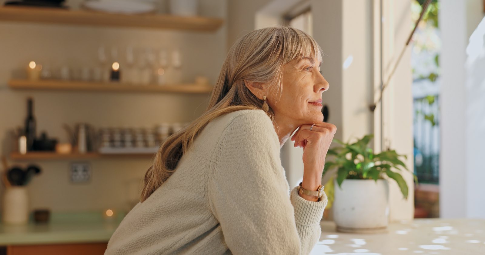 An older woman looking thoughtfully out of a window